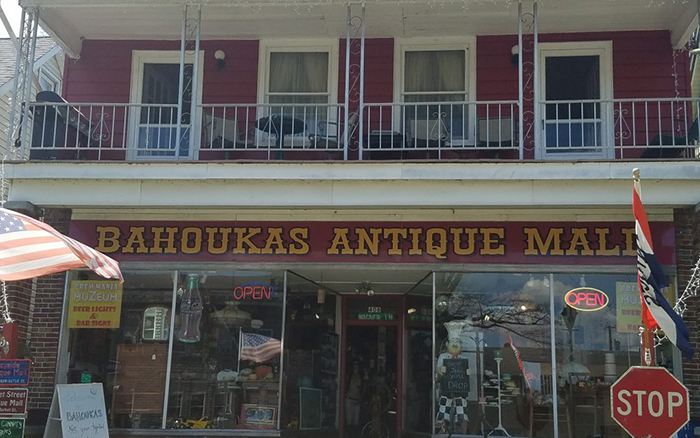 Two story red antique shop building with white windows and second story porch