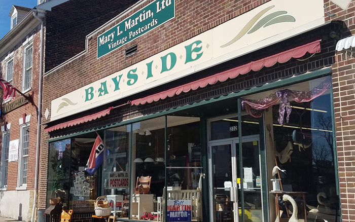 Brick storefront on a city with red and white awnings.