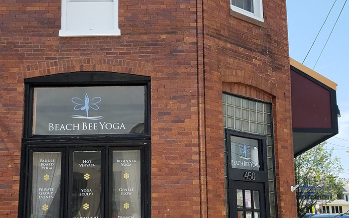 Corner view of a brick storefront with large window panels with black trim