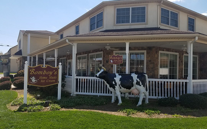 Corner view of large ice cream shop with a ceramic cow out front.