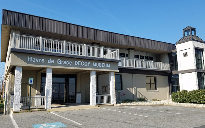 Two story tan museum building with wrap around upper porch.