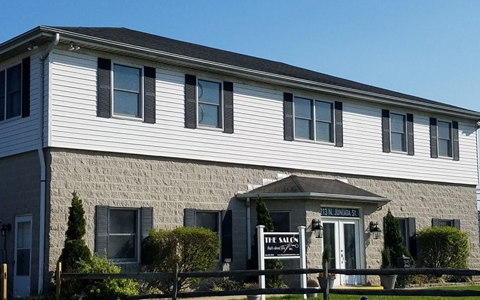 Two story stone building with sign out front reading "The Salon"