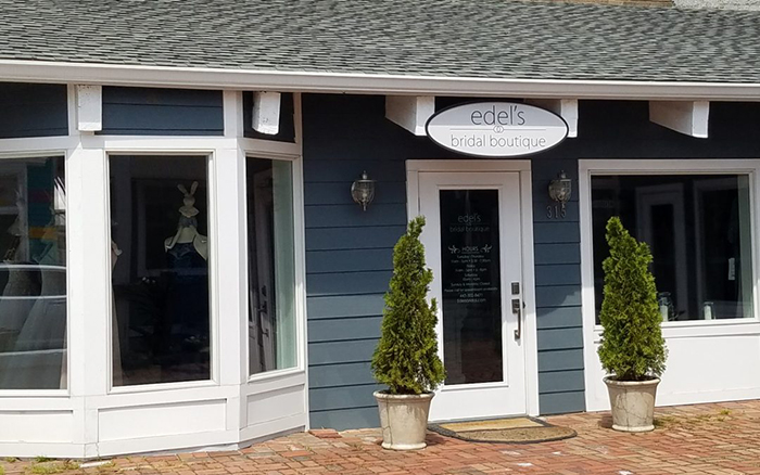 Storefront view of a blue and white bridal boutique with brick paving.