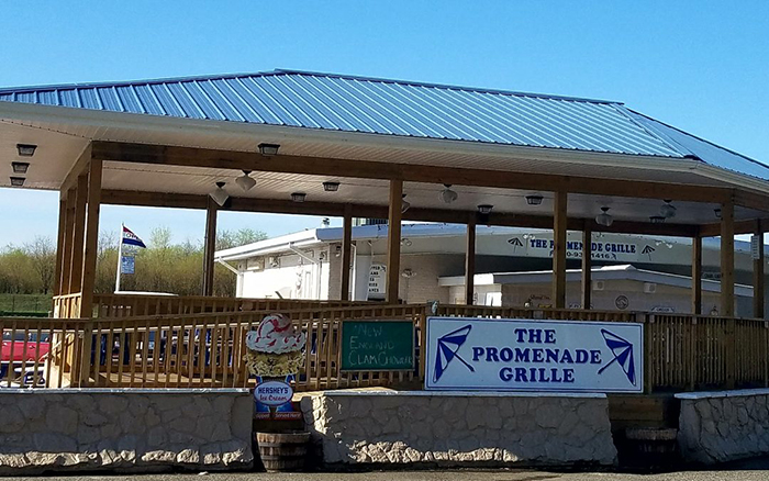 Outdoor wooden covered dining deck with sign that reads The Promenade Grille