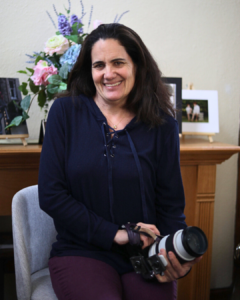 Photography studio owner in Havre de Grace, Maryland, smiling with camera in hand