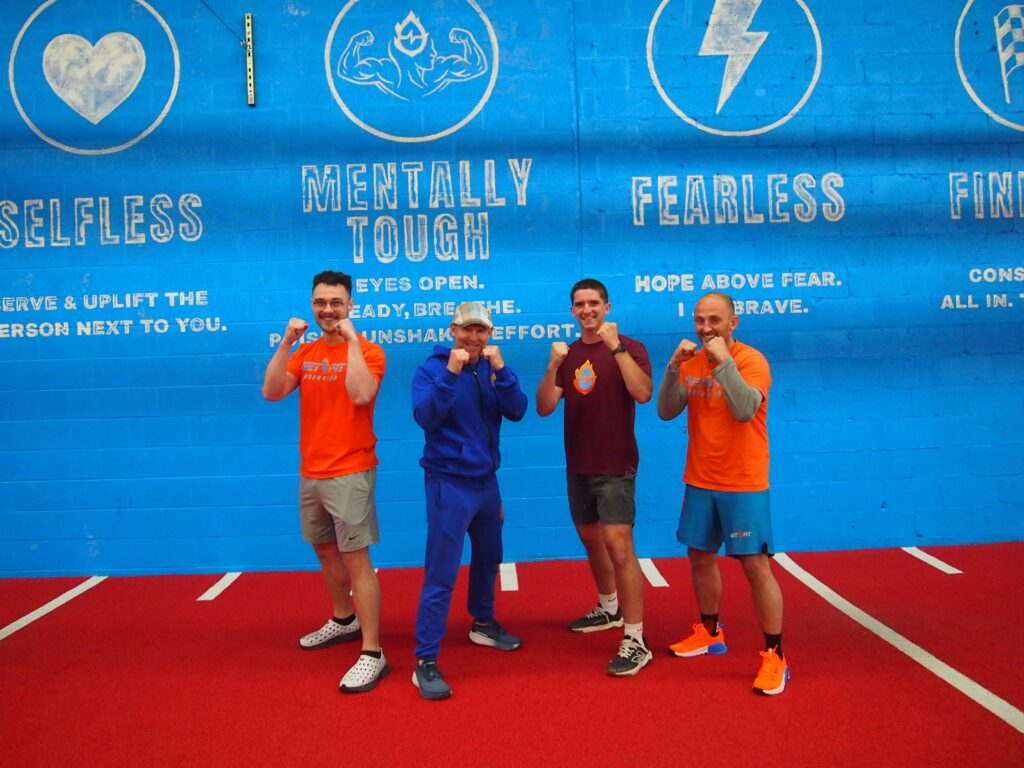 Get Fit Gym team striking boxing poses in front of a blue gym wall on orange turf